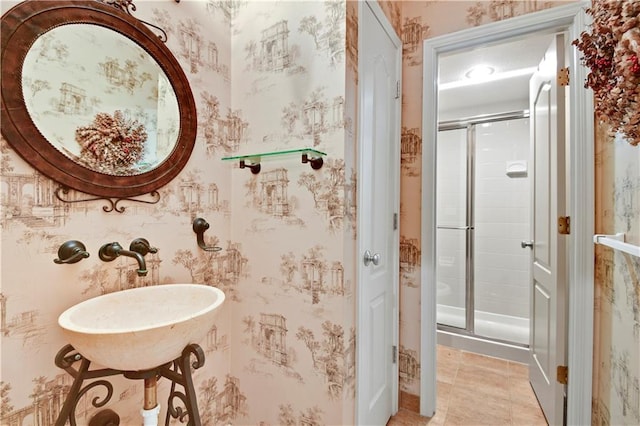 full bathroom featuring wallpapered walls, a shower stall, tile patterned flooring, and a sink