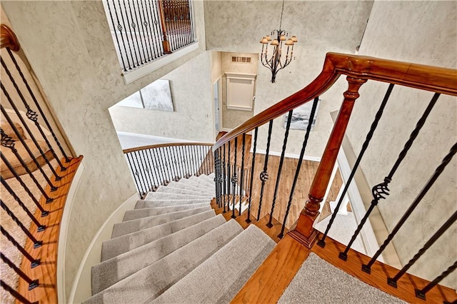 stairway featuring visible vents, an inviting chandelier, and wood finished floors