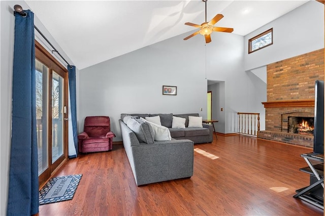 living room featuring a brick fireplace, wood finished floors, high vaulted ceiling, and ceiling fan