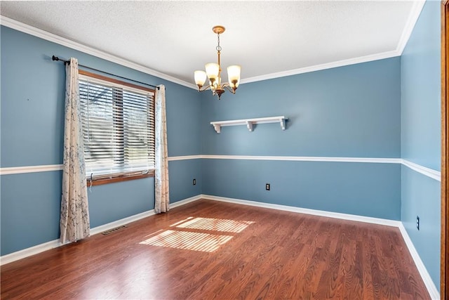 spare room with baseboards, a chandelier, ornamental molding, wood finished floors, and a textured ceiling