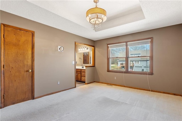 unfurnished bedroom with baseboards, a raised ceiling, light carpet, and a chandelier