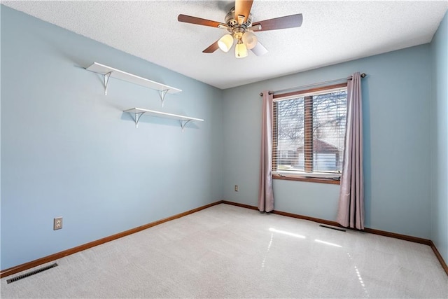 spare room featuring visible vents, baseboards, a textured ceiling, and carpet floors