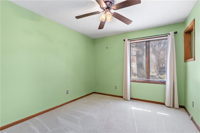 carpeted spare room featuring ceiling fan, visible vents, baseboards, and a textured ceiling