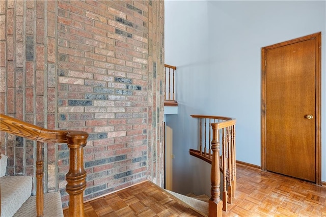 stairway with brick wall and baseboards