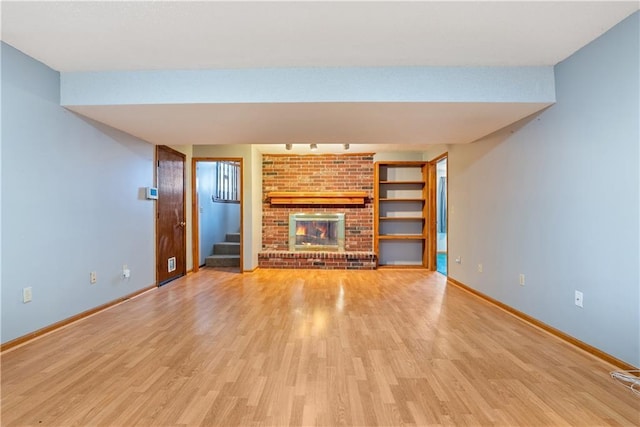 unfurnished living room with stairway, baseboards, and light wood finished floors