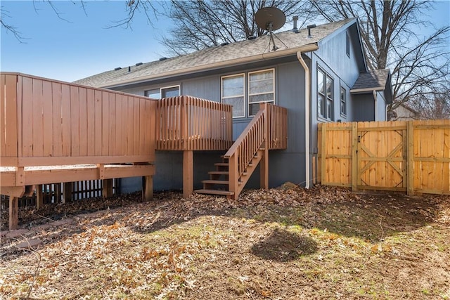 back of house featuring a gate, fence, a wooden deck, a shingled roof, and stairs