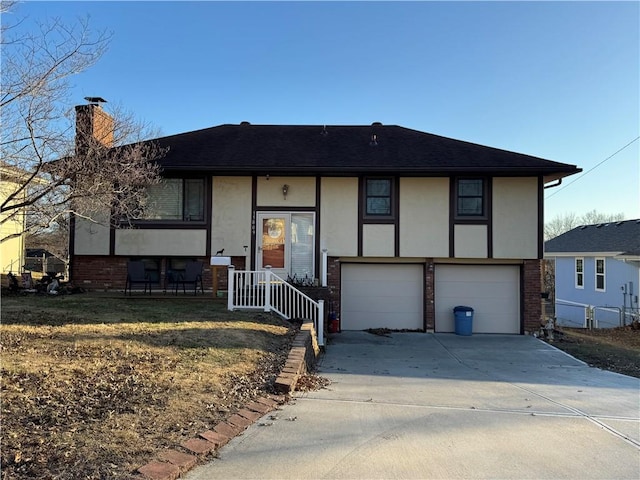 split foyer home with stucco siding, concrete driveway, a garage, brick siding, and a chimney