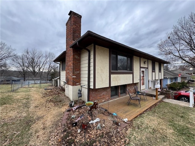 view of front of home featuring stucco siding, a chimney, a front lawn, and fence