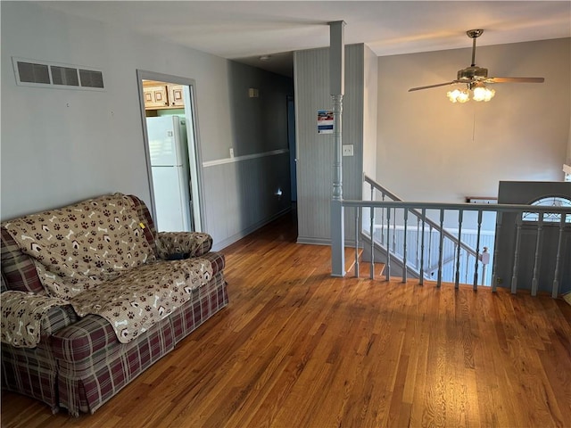 living area featuring an upstairs landing, visible vents, a ceiling fan, and wood finished floors