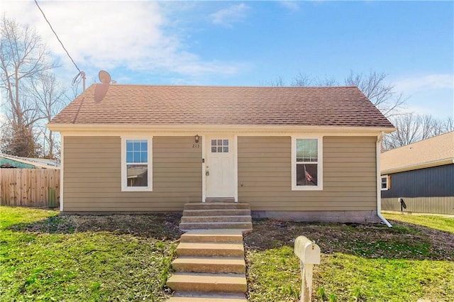 bungalow-style house featuring entry steps, fence, and roof with shingles