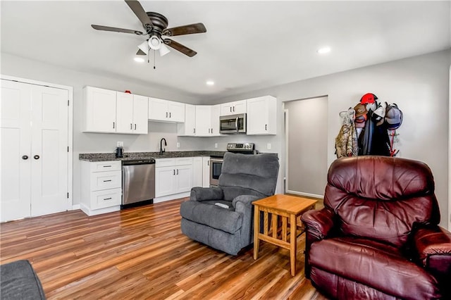 interior space featuring a sink, stainless steel appliances, light wood-style floors, dark countertops, and open floor plan