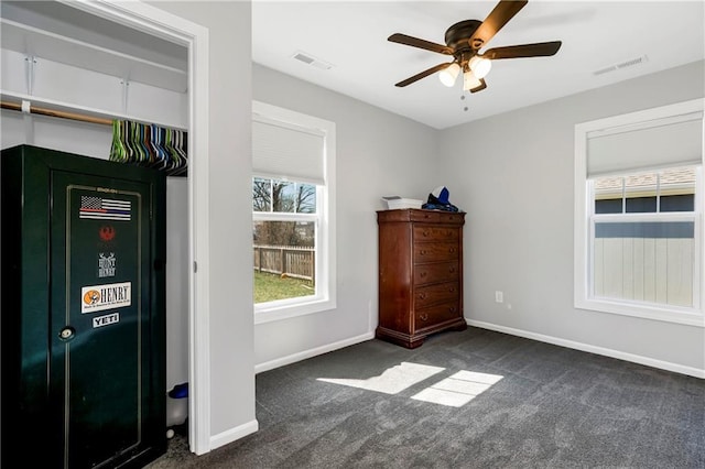 interior space with baseboards, visible vents, and dark colored carpet