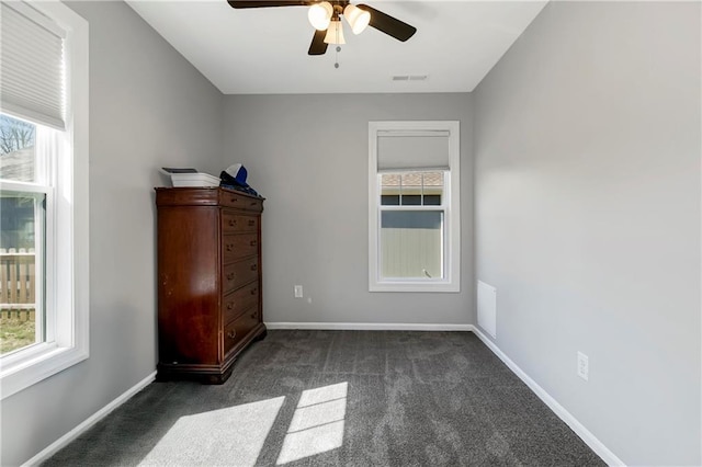 unfurnished bedroom featuring multiple windows, baseboards, visible vents, and dark carpet