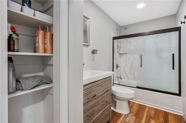 full bathroom featuring combined bath / shower with glass door, toilet, vanity, and wood finished floors