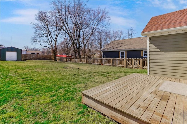 view of yard featuring a wooden deck, a fenced backyard, and an outdoor structure