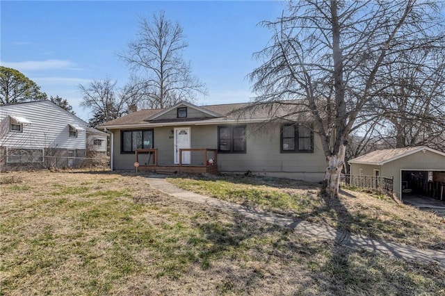 view of front facade with a detached garage, a front yard, and fence