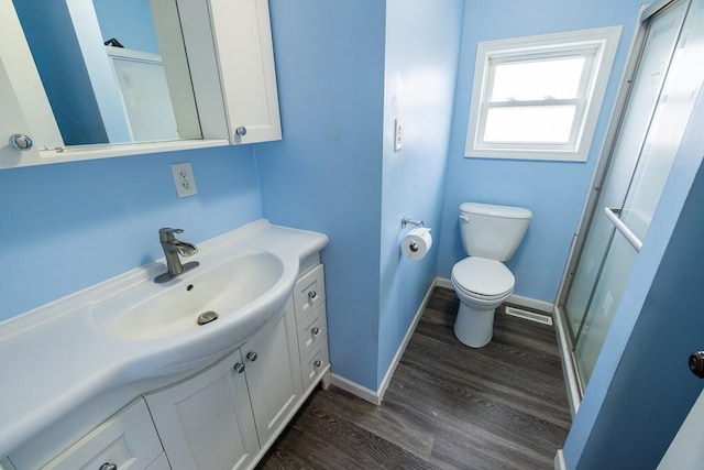 full bath with vanity, wood finished floors, baseboards, a shower stall, and toilet