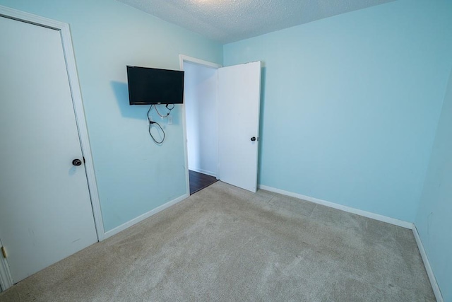 unfurnished bedroom with baseboards, a textured ceiling, and carpet