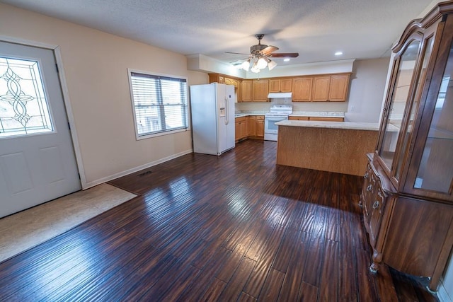 kitchen with a textured ceiling, dark wood finished floors, white appliances, a peninsula, and light countertops