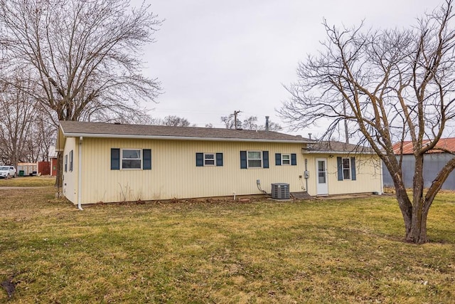 rear view of property with central air condition unit and a yard