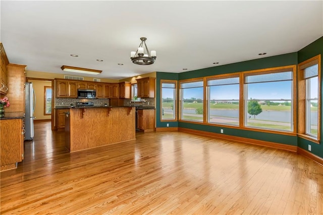 1796 NW 770th Rd, Bates City, MO 64011 - kitchen with appliances with stainless steel finishes, brown cabinets, tasteful backsplash, dark countertops, and light wood-style flooring