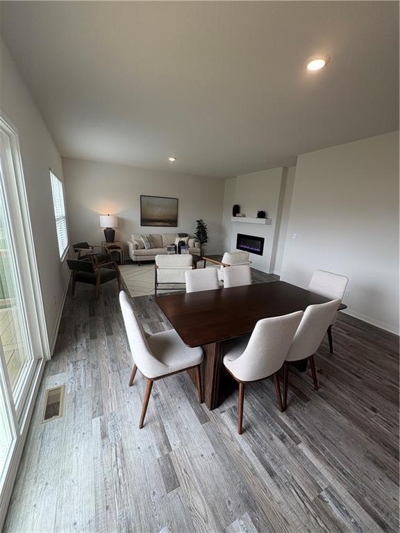 dining area featuring visible vents, baseboards, recessed lighting, a fireplace, and wood finished floors