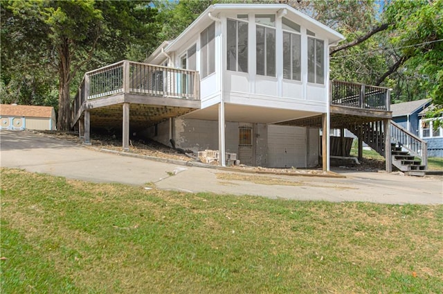 back of house featuring a wooden deck, an attached garage, a sunroom, stairs, and a carport