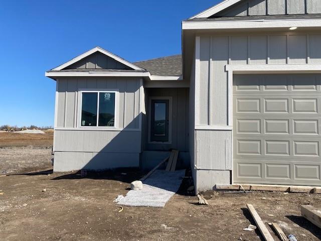 exterior space featuring board and batten siding, an attached garage, and a shingled roof