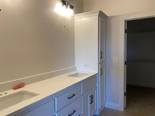 bathroom with double vanity, baseboards, and a sink