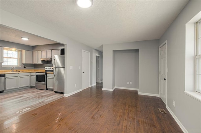 kitchen with under cabinet range hood, visible vents, appliances with stainless steel finishes, and a sink