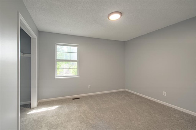 unfurnished bedroom featuring carpet flooring, baseboards, visible vents, and a textured ceiling