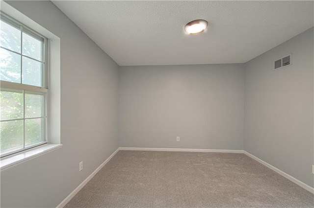 unfurnished room featuring visible vents, a textured ceiling, baseboards, and carpet floors