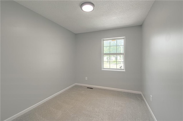 empty room with a textured ceiling, light colored carpet, visible vents, and baseboards