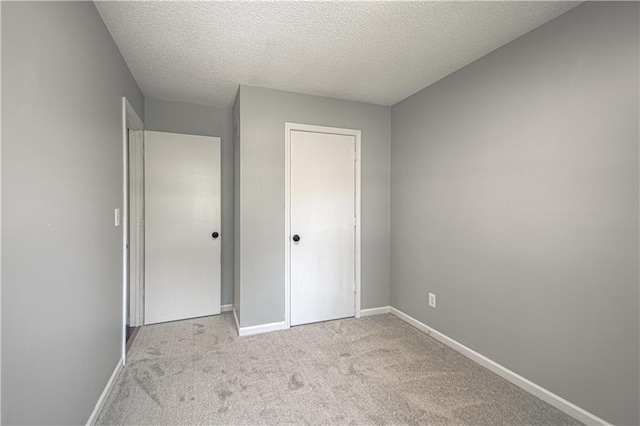 unfurnished bedroom featuring carpet flooring, baseboards, a closet, and a textured ceiling