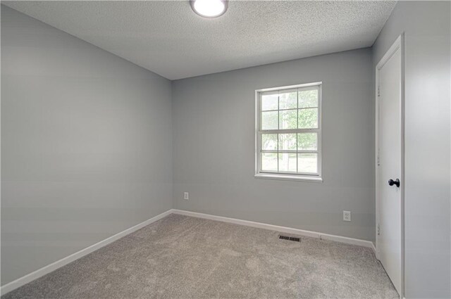 unfurnished bedroom with a textured ceiling, carpet, visible vents, and baseboards