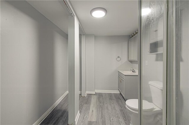 bathroom featuring baseboards, toilet, wood finished floors, and vanity