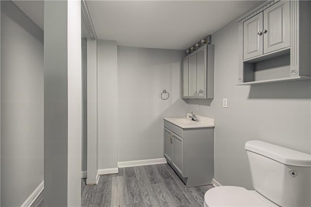 bathroom featuring toilet, vanity, baseboards, and wood finished floors