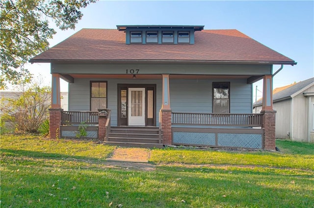 view of front facade featuring a porch, a front yard, and roof with shingles