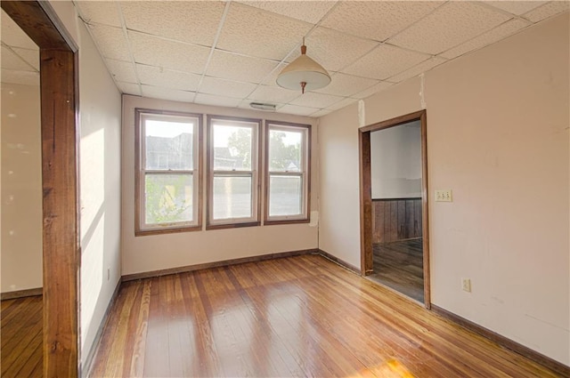 empty room with a drop ceiling, baseboards, visible vents, and light wood-style flooring