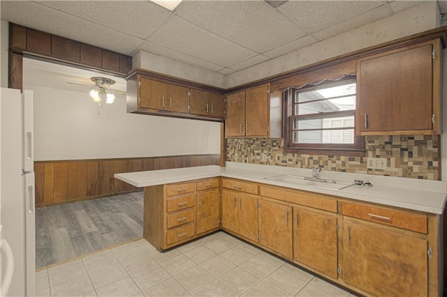 kitchen with a wainscoted wall, light countertops, freestanding refrigerator, and a sink