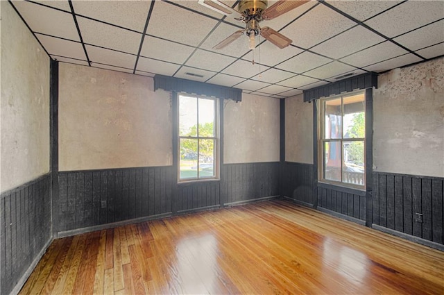 unfurnished room featuring a drop ceiling, wainscoting, visible vents, and wood-type flooring