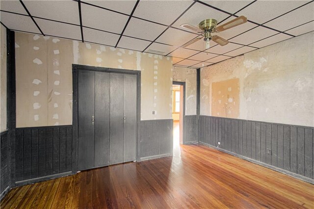 unfurnished room with a wainscoted wall, a paneled ceiling, and wood finished floors