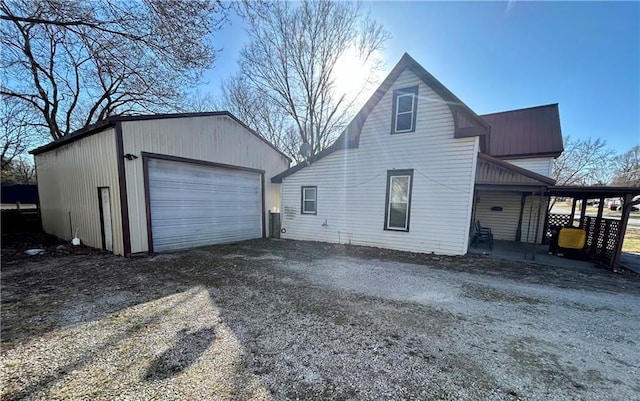 view of side of home with an outbuilding, a garage, driveway, and metal roof