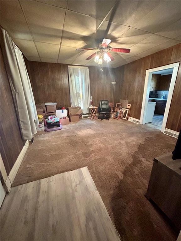 unfurnished room with carpet, a ceiling fan, wood walls, and a paneled ceiling