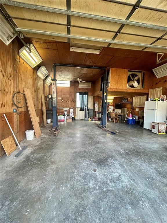 garage with wood walls and freestanding refrigerator