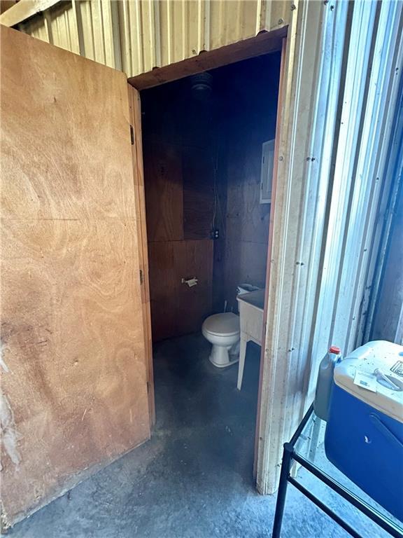 bathroom with unfinished concrete floors and toilet