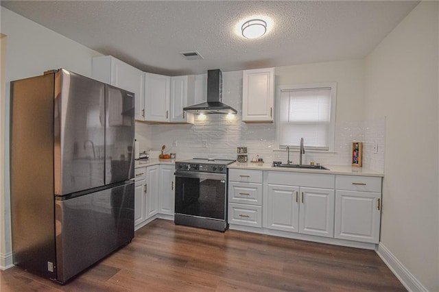 kitchen with wall chimney range hood, dark wood finished floors, light countertops, electric range oven, and freestanding refrigerator