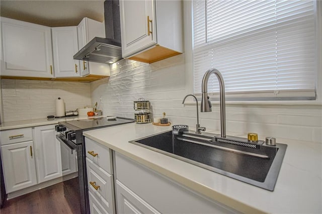 kitchen featuring white cabinetry, black range with electric stovetop, wall chimney range hood, and a sink