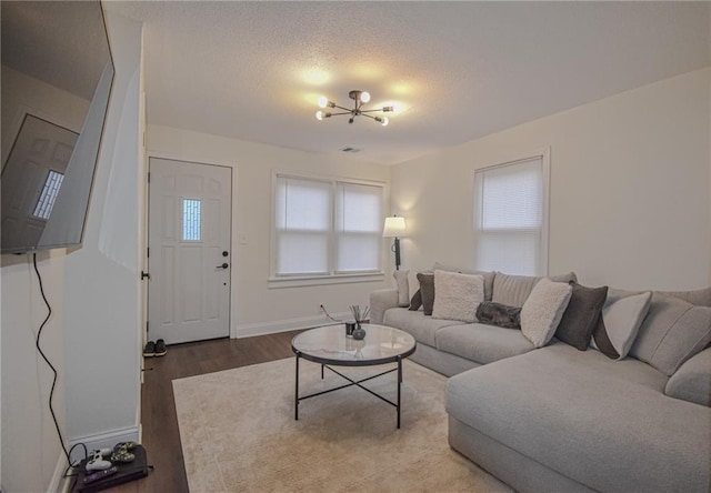 living area featuring visible vents, baseboards, wood finished floors, a notable chandelier, and a textured ceiling