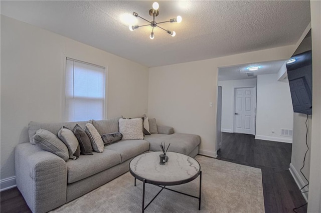 living room featuring visible vents, a textured ceiling, baseboards, and wood finished floors